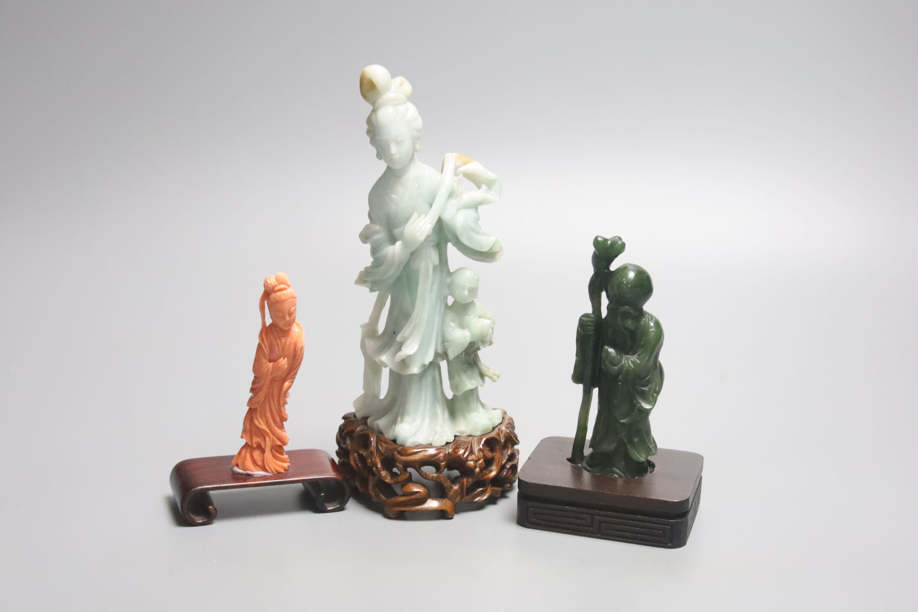 A Chinese coral figure of a lady, 9cm, a Chinese jadeite group of Guanyin with stand 19.5cm and a spinach green jade figure of Shou Lao